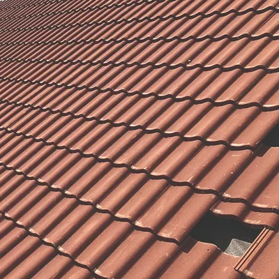 Close-up of terracotta roof tiles with one tile slipped out of line