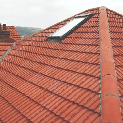 Red tiled hip roof with a roof window, hills in the distance