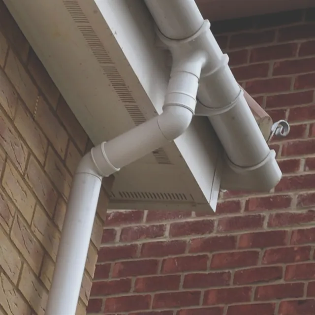 White uPVC gutter, downpipe and vented soffit on a brick corner